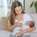 BBLüv Mumpulse 3-in-1 lactation massager used by a mother holding a newborn baby on a couch.
