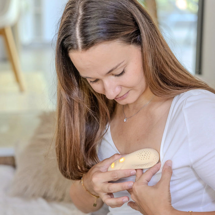 BBLÜS Mumpulse 3-in-1 Lactation Massager being used by a woman on her chest at home.