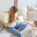BBLÜV Mumpulse 3-in-1 lactation massager used by a woman on a sofa beside a child.