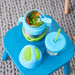 bbox insulated food jar 335ml ocean breeze filled with pasta and veggies on a blue table next to a straw cup.