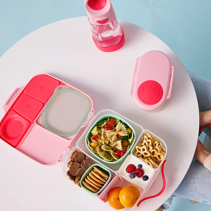 bbox lunchbox Flamingo Fizz open on a table, filled with pasta salad, fruit, snacks, and a water bottle