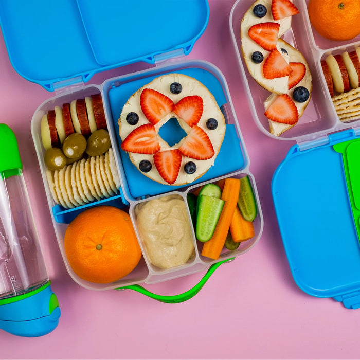 Bbox lunchbox Ocean Breeze filled with fruit bagel, crackers, veggies and dip on pink background.