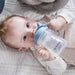b.box silicone sippy cup in blue held by a baby lying on a soft white blanket