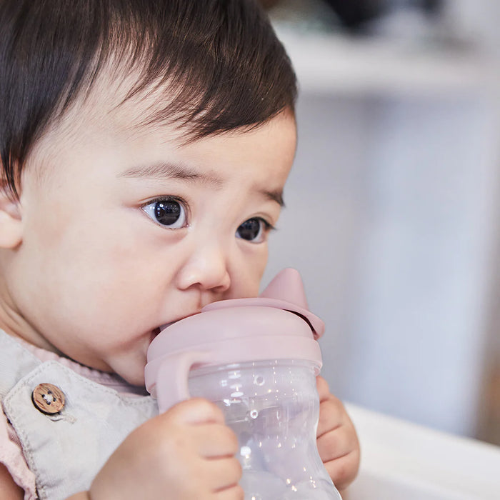 bbox training silicone sippy cup blush held by baby drinking at home