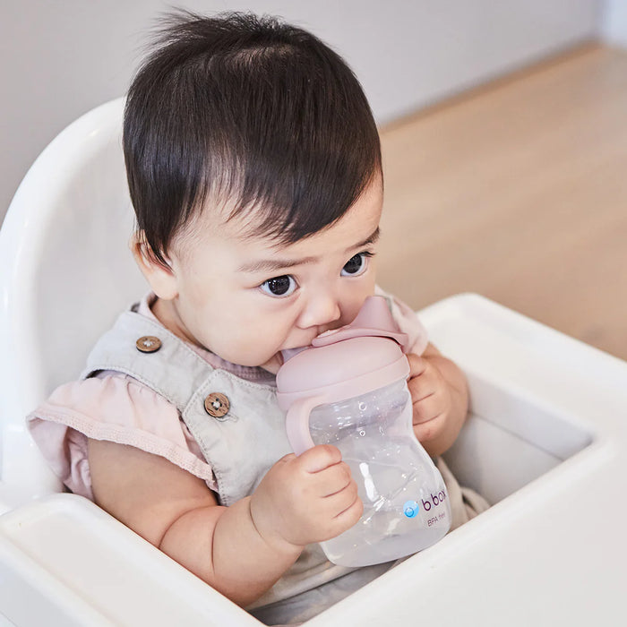 bbox silicone sippy cup blush held by baby sitting in high chair