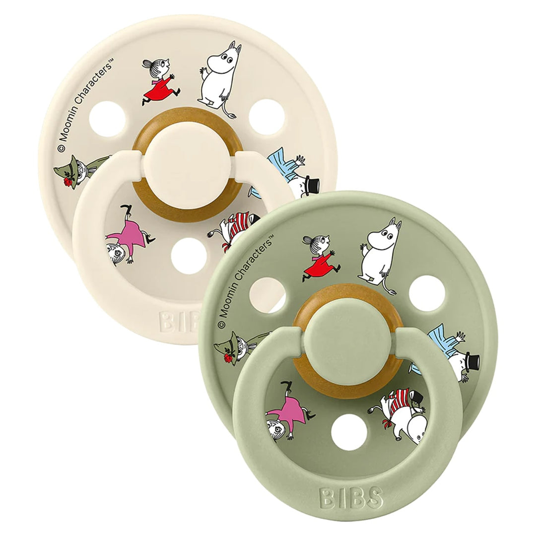 Two round latex pacifiers with Moomin character prints in ivory and sage green colors