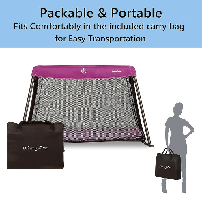 Dream On Me travel crib in light pink with black mesh sides, shown with included carry bag and silhouette holding it.