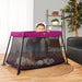 Dream On Me Travel Light Playard in pink shown with a baby standing inside in a living room.