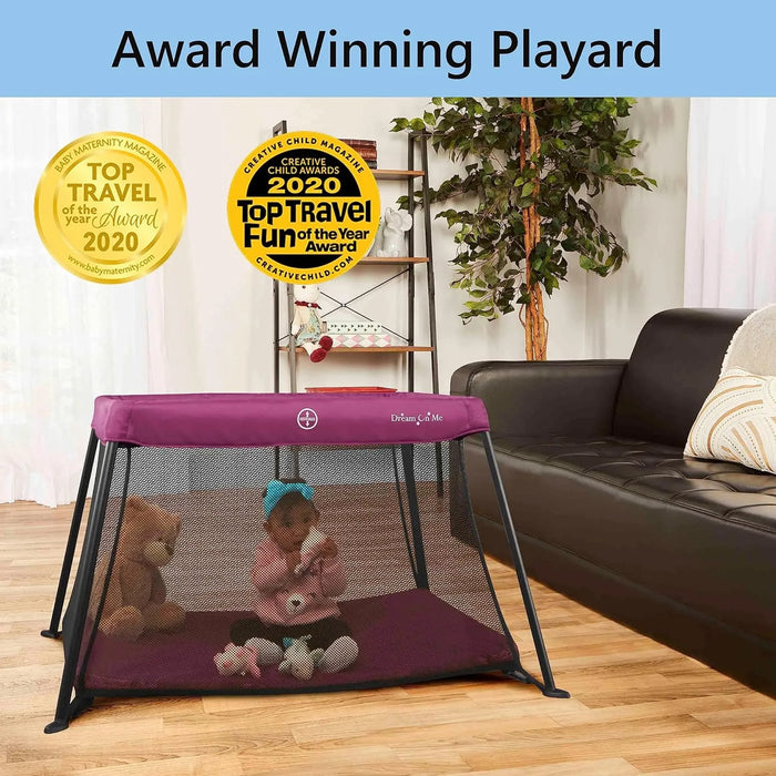 Dream On Me Travel Light Pink playard with a baby inside, set up in a living room next to a sofa.