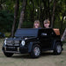 Kids electric ride-on Mercedes G63 car with two children sitting inside, shown outdoors in a park.