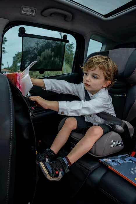 Ezimoov Sun Roller car window shade installed on a car window behind a child in a booster seat.