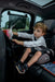 Ezimoov Sun Roller car window shade installed on a car window behind a child in a booster seat.