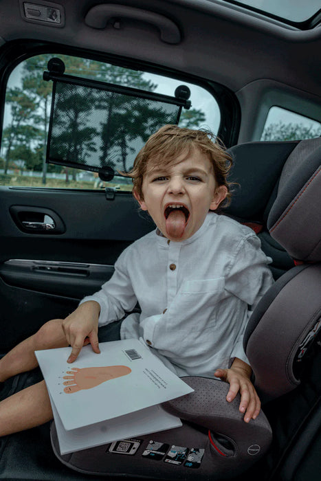 Ezimoov Sun Roller car window shade installed on rear window with child in car seat inside vehicle.