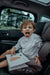 Ezimoov Sun Roller car window shade installed on rear window with child in car seat inside vehicle.