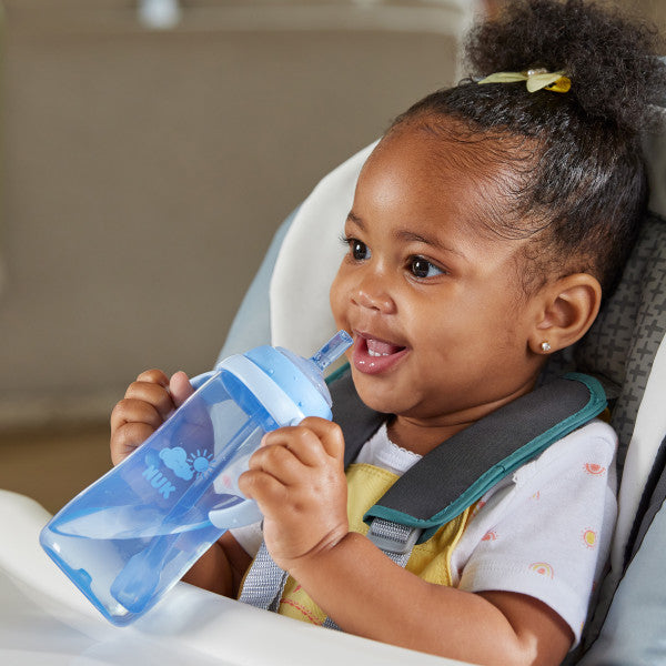 NUK blue straw cup held by smiling baby sitting in a high chair