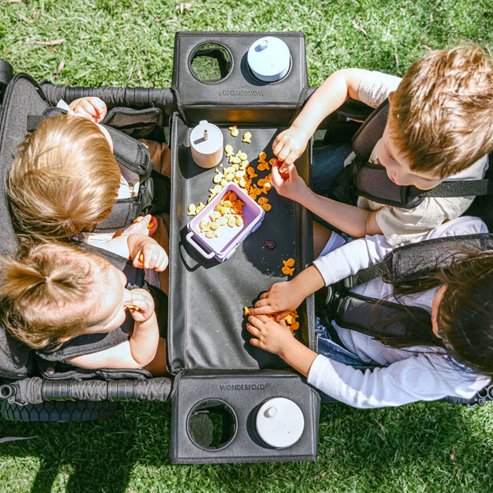Wonderfold Flex Snack Tray L2-L4 installed in stroller wagon with children snacking outdoors.