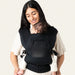 Flybaby 3D Baby Carrier in black shown worn by a parent carrying a baby on their chest indoors.