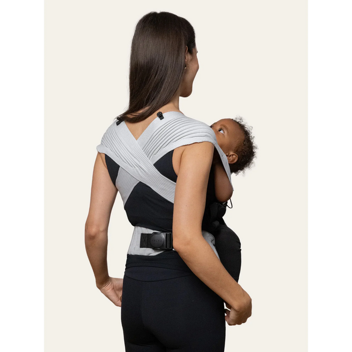 Flybaby 3D baby carrier shown on a woman carrying an infant facing inward.