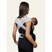 Flybaby 3D baby carrier shown on a woman carrying an infant facing inward.
