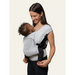 Flybaby 3D baby carrier in light grey, worn by a smiling woman holding an infant close to her chest.