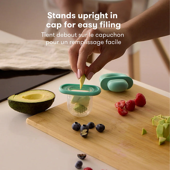 Frida Baby Push Pop Feeder standing upright on a kitchen counter as fruit is placed inside.