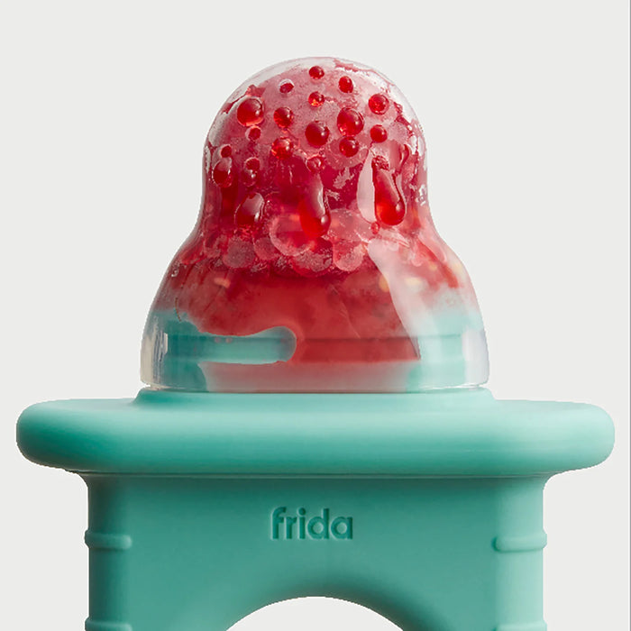 Frida Baby Push Pop Feeder with red frozen fruit inside on a plain background.