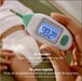 Frida Baby Quick-Read Rectal Thermometer held in hand, digital display showing 98.7°F, baby in background.