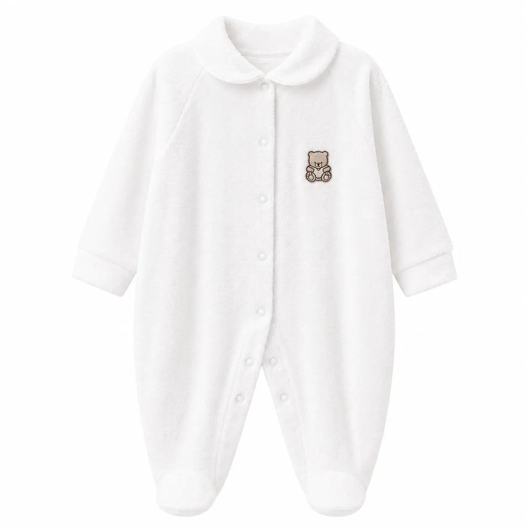 White baby pyjama with teddy bear patch on chest, displayed flat on a plain background.