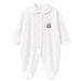 White baby pyjama with teddy bear patch on chest, displayed flat on a plain background.