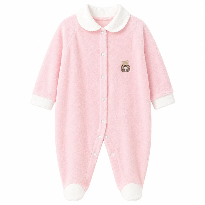 Pink baby pyjama with white trim and teddy bear embroidery, laid flat on a white background.