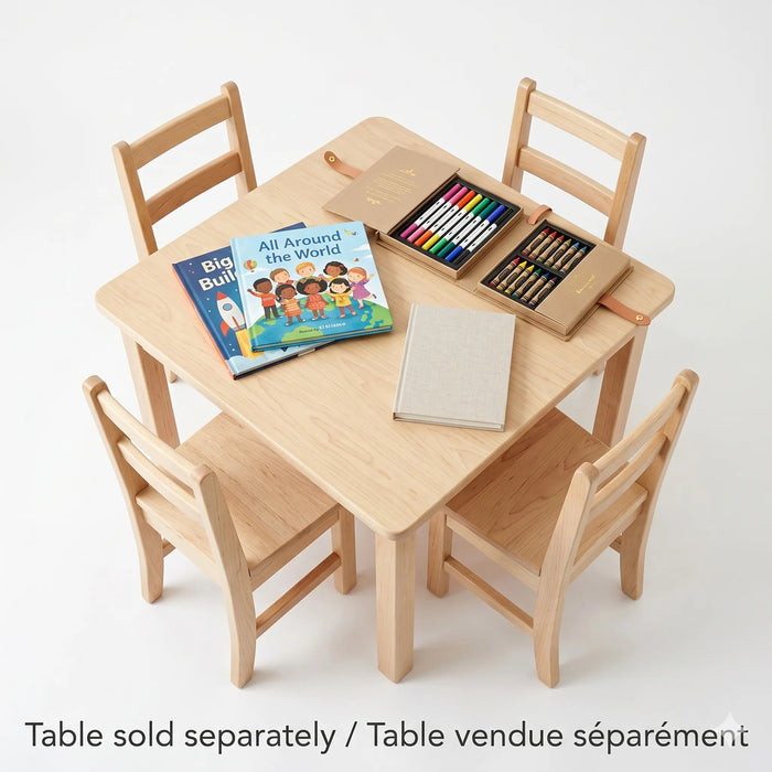 A top-down product photograph of a solid wood square kids activity table with four matching chairs. The table features curated modern children's books and art supplies. Bilingual text clarifies: "Table sold separately / Table vendue séparément"