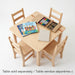 A top-down product photograph of a solid wood square kids activity table with four matching chairs. The table features curated modern children's books and art supplies. Bilingual text clarifies: "Table sold separately / Table vendue séparément"