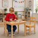 Child playing with a puzzle at a solid wooden table with chairs in a classroom setting - Goldtex