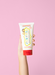 Jack N' Jill Strawberry Natural Toothpaste held in a hand against a pink background.