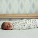 Koala Baby 4-Pack Flannel Receiving Blankets with woodland prints, wrapped around a sleeping baby on a bed.