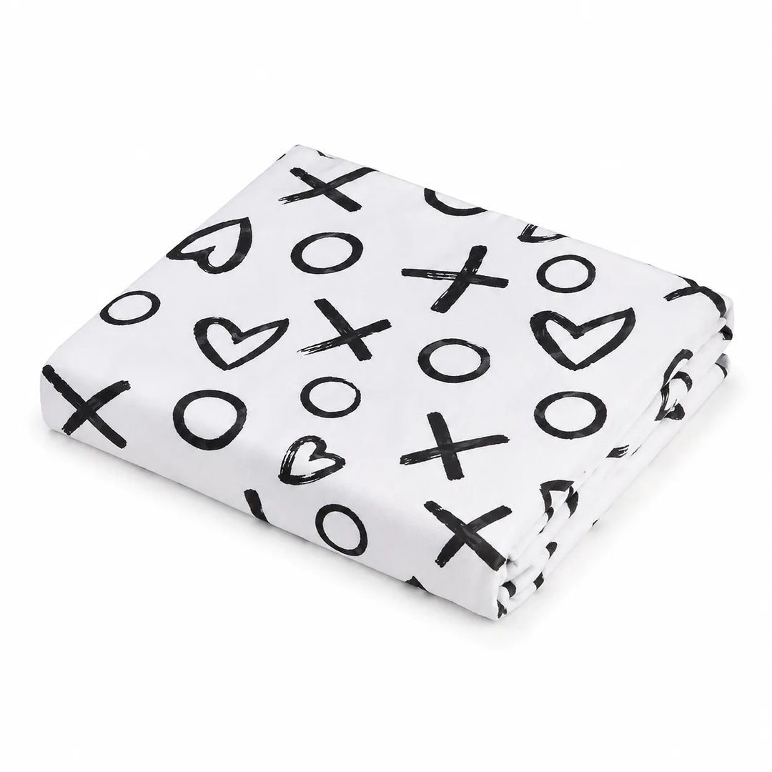 Kushies jersey fitted crib sheet folded, white with black X, O, and heart pattern.