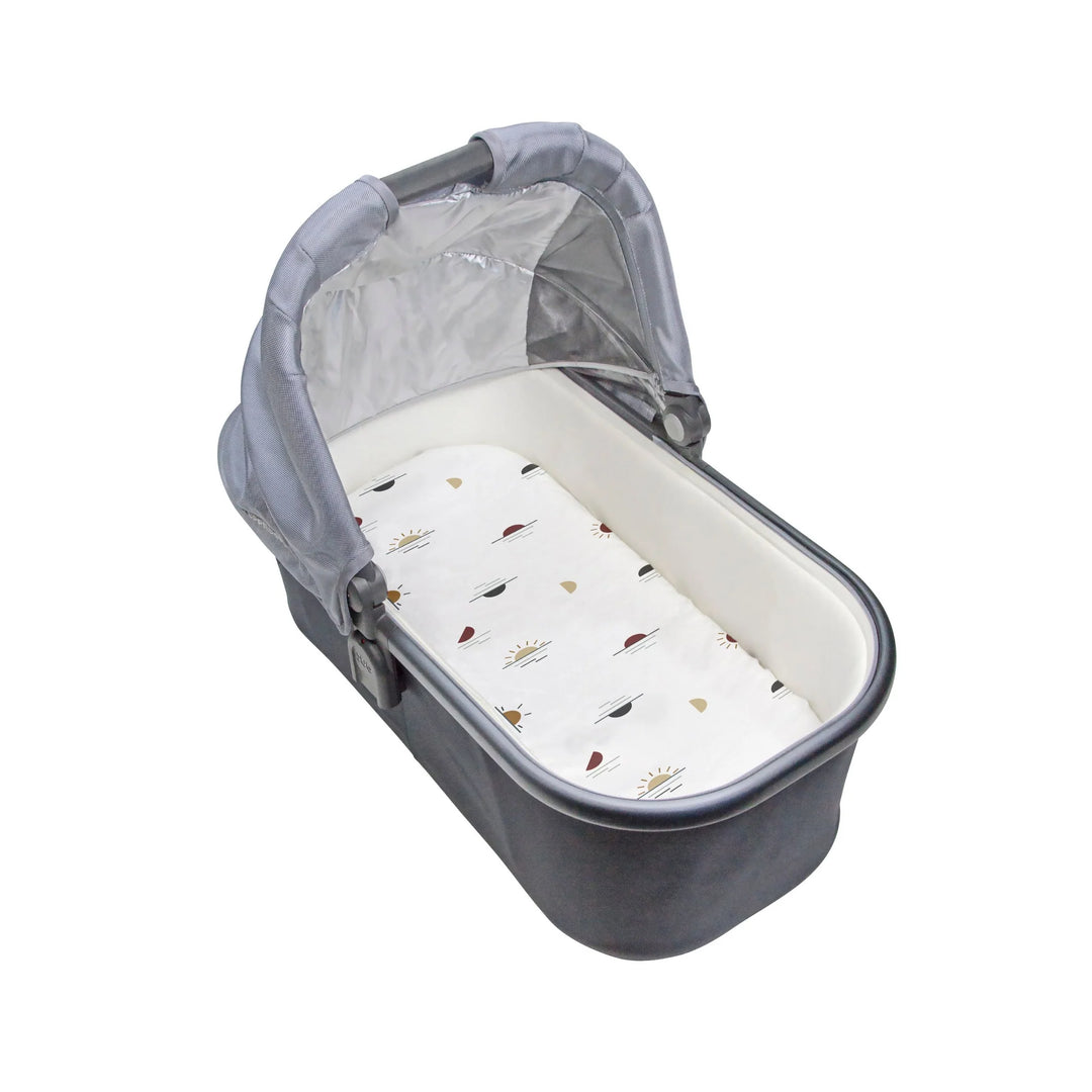 White percale bassinet sheet with minimal sun and leaf print in a grey baby bassinet