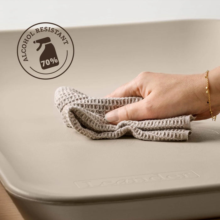 Leander Matty baby changing waterproof mat being wiped clean by hand with a cloth.