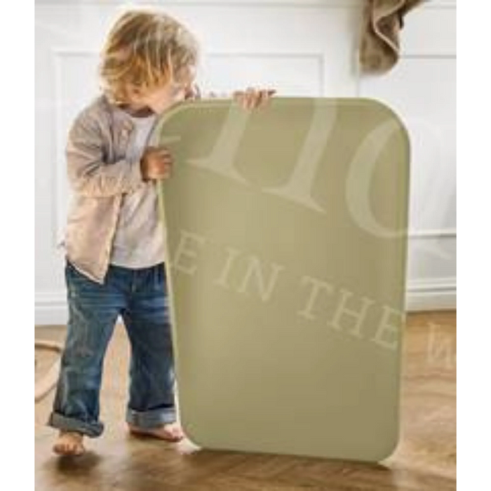 Leander Matty baby changing waterproof mat held upright by a child indoors on wood floor.