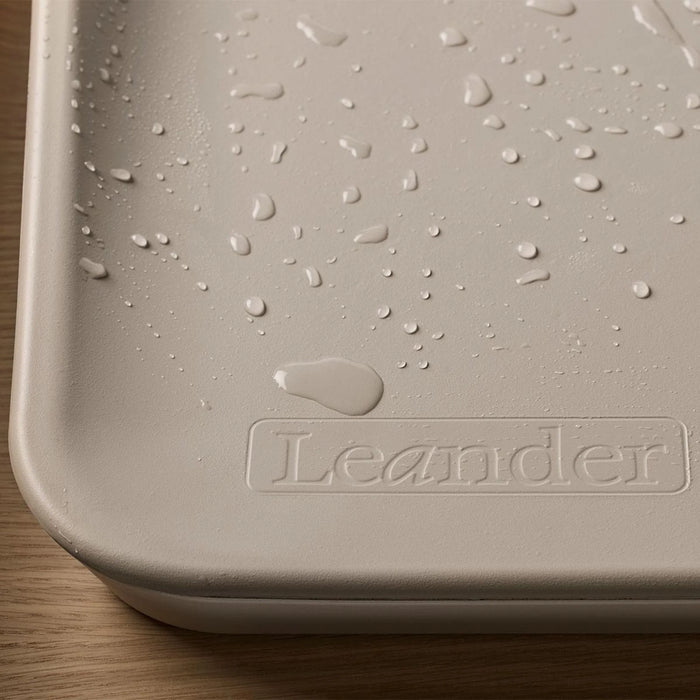 Leander Matty baby changing waterproof mat with water droplets on a wooden surface.