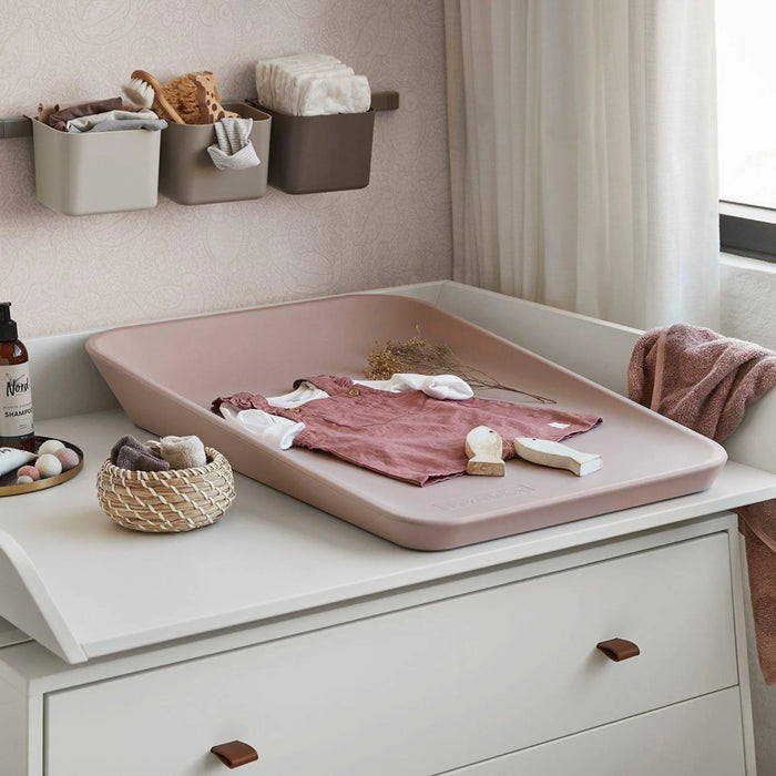 Leander Matty baby changing waterproof mat on a nursery dresser with baby clothes placed on top.