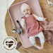 Leander Matty baby changing waterproof mat with smiling baby lying on it on woven rug.