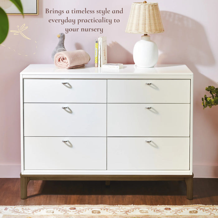 Little Seeds Laurel 6-drawer dresser in white shown in a nursery with books, a lamp, and decor on top.