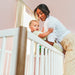 Little Seeds Laurel Island Convertible Crib with mother placing baby inside in a softly lit nursery.