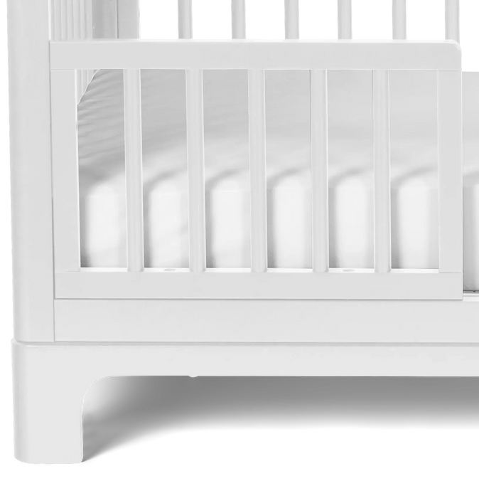 Little Seeds Spindle guardrail in white attached to a crib, shown from the side.