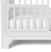 Little Seeds Spindle guardrail in white attached to a crib, shown from the side.