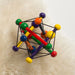 Manhattan Toy Skwish wooden rattle teether in bright colors resting on a soft cream surface.
