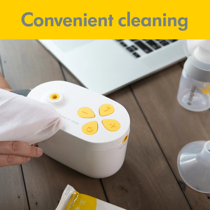 Medela Quick Clean Breast Pump Wipes being used to clean a breast pump unit on a wooden table.
