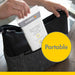 Medela Quick Clean breast pump wipes being placed into a diaper bag on a wooden table.