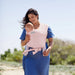 Moby Easy Wrap Baby Carrier in rose worn by a woman holding an infant outdoors on a sunny day.
